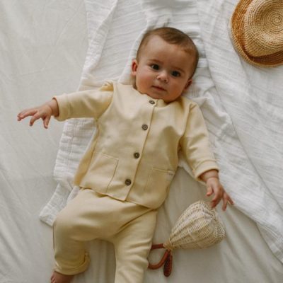 Bebé Con Conjunto De Dos Piezas Amarillo Pastel Sobre Una Cama